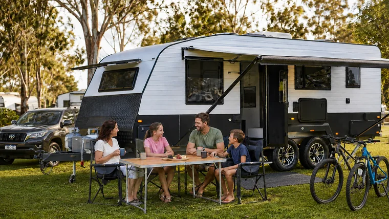 Australian family relaxing beside a modern caravan at a regional caravan park